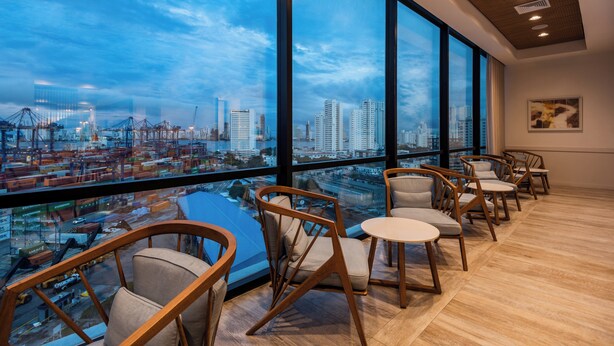 A modern hotel room with large windows offering a city view, wooden chairs, and a small table. - Holiday Inn Express Cartagena Manga by IHG (Cartagena)