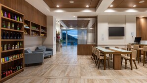 A modern hotel lobby with wooden shelves, seating areas, a dining table, and a large TV screen. - Holiday Inn Express Cartagena Manga by IHG (Cartagena)