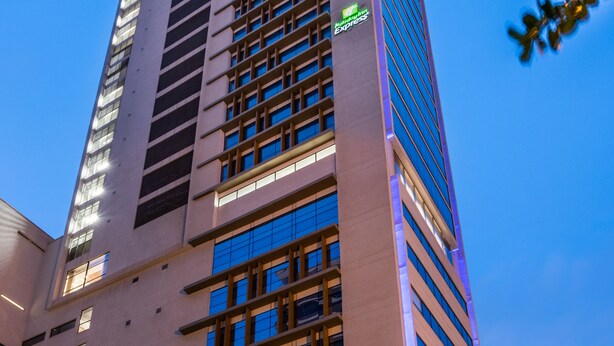 A tall, modern hotel building with a prominent vertical design, large windows, and a visible green sign indicating the name. - Holiday Inn Express Cartagena Manga by IHG (Cartagena)