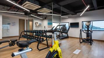 Un gimnasio con equipo de ejercicio, cinta de correr y remo.