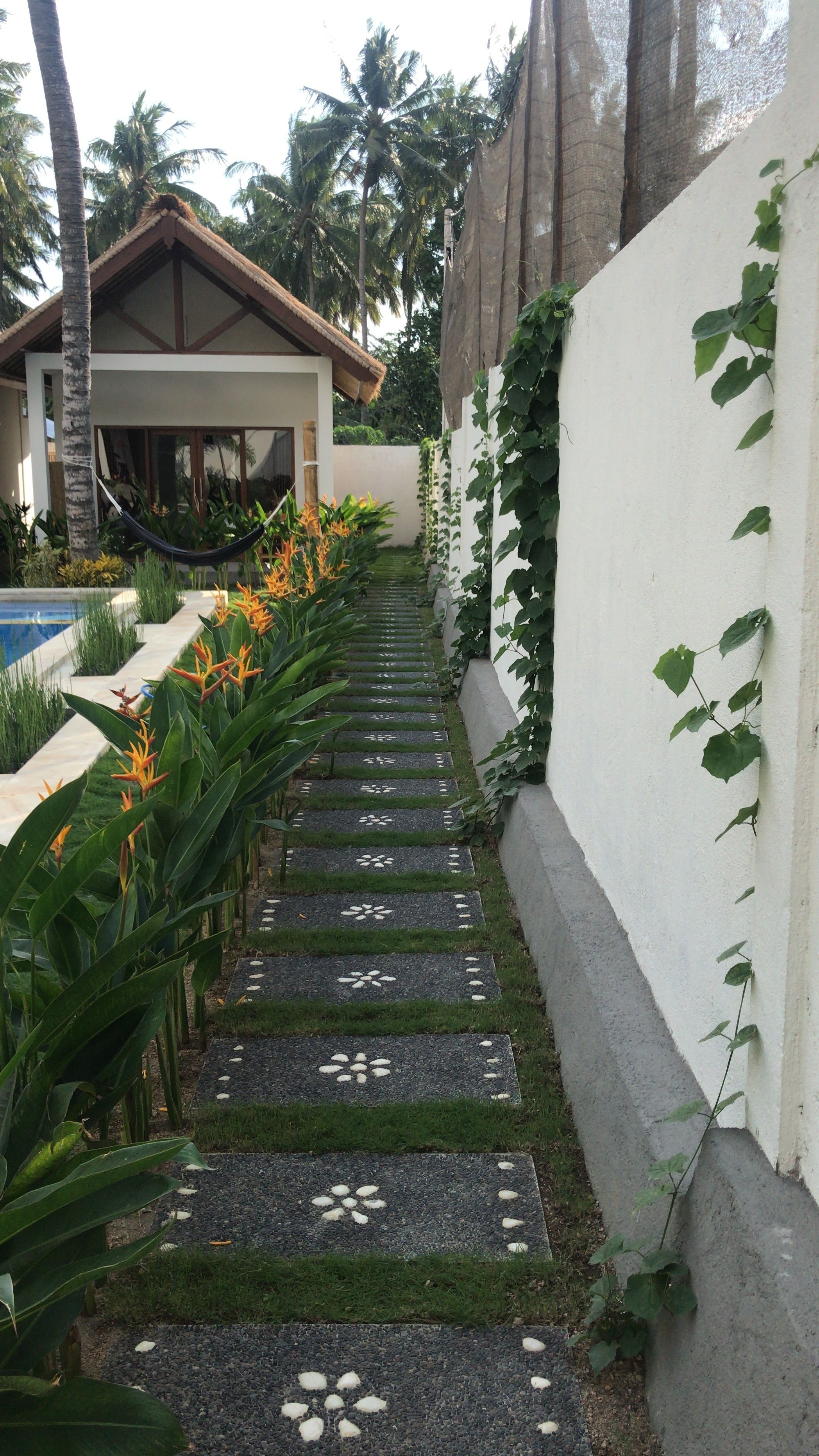 Un chemin bordé de pierres décoratives mène à un bâtiment dont le toit est recouvert de tuiles.