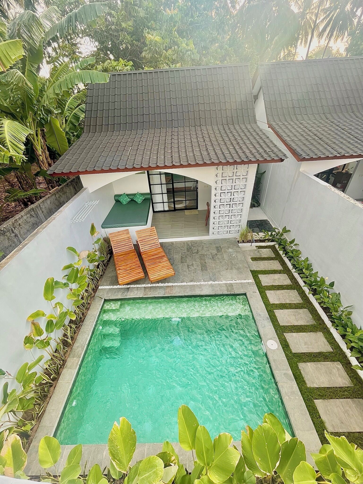 Een woonhuis met een zwembad, een overdekt terras en een tuin.