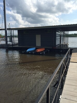 A dock with a small building, kayaks, and a calm body of water. - FLOATING Apartment. Enchanting Lake Views, Sunsets, FUN (Monroe)
