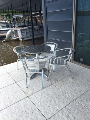 A patio area with a table and chairs, a boat, and a glass door leading to a covered area. - FLOATING Apartment. Enchanting Lake Views, Sunsets, FUN (Monroe)