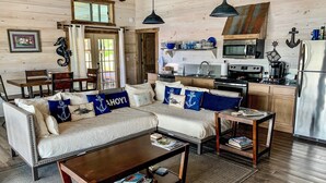 A cozy living room with a sofa, coffee table, and a dining area with a table and chairs. - FLOATING Apartment. Enchanting Lake Views, Sunsets, FUN (Monroe)