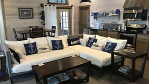 A cozy living room with a sofa, coffee table, and a kitchen area with modern appliances. - FLOATING Apartment. Enchanting Lake Views, Sunsets, FUN (Monroe)