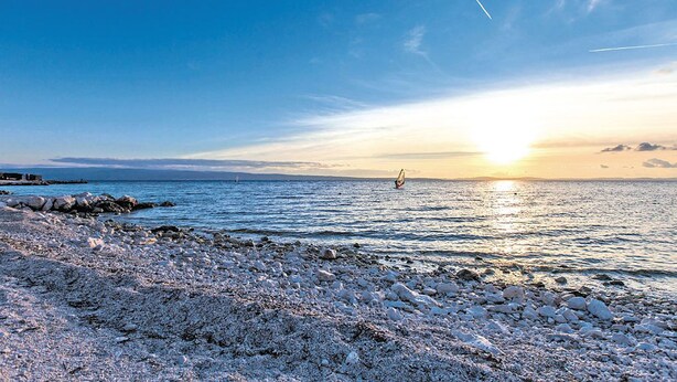 A rocky beach with a sunset over the water.