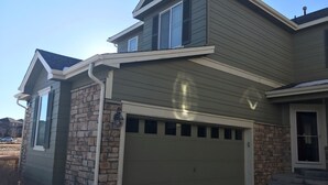 A two-story house with a garage, stone foundation, and a chimney. - A Fabulous home in the Rocky Mountain State (Centennial)