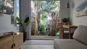Un salon moderne doté d’une porte-fenêtre coulissante donnant sur un jardin luxuriant.