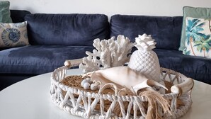 Ein Wohnzimmer mit blauem Sofa, einem weißen Couchtisch und einem Bild von einer Strandlandschaft.