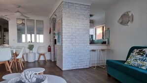 Ein modernes Wohnzimmer mit einem türkisfarbenen Sofa, einem runden Couchtisch und einer Wand mit weißen Ziegeln.