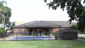 A building with a brick facade, a tiled roof, and a fenced area with a pool.