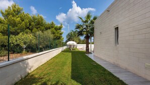 A courtyard with a well-maintained lawn, a palm tree, and a building with a brick facade.