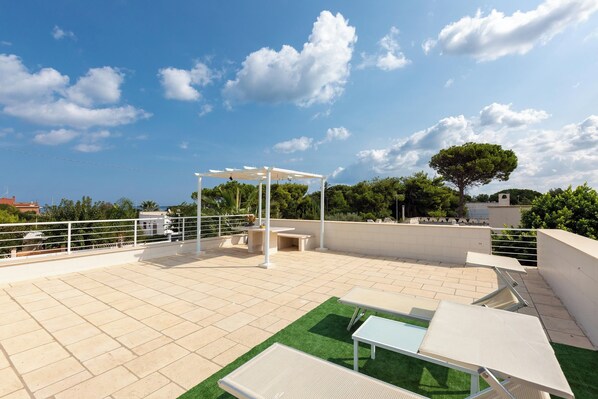 Una terraza en la azotea con pérgola, asientos y vistas de la ciudad.