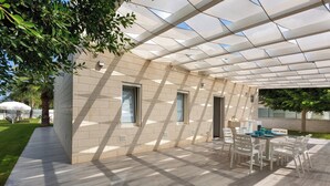 A covered outdoor area with a table and chairs, a tiled floor, and a glass ceiling.