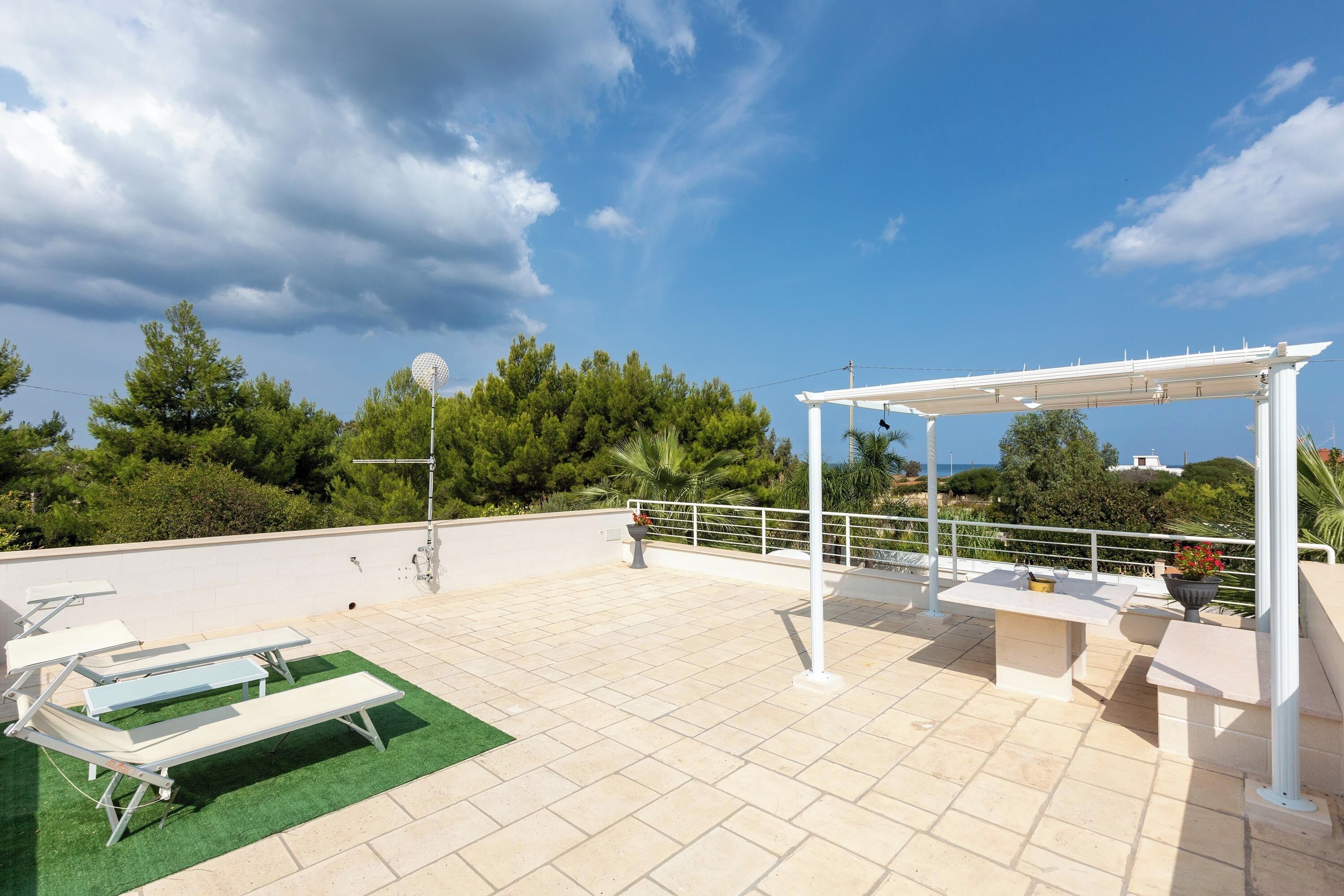 Eine Dachterrasse mit Außenmöbeln, einer Pergola und einer Windturbine.