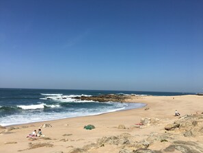 A beach with rocky terrain and people relaxing. - Cozy Beach Front with Rooftop (Vila do Conde)