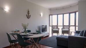Ett modernt vardagsrum med en matplats, en platt-TV och ett stort fönster med fin utsikt.
