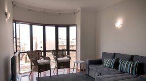 A balcony with wicker chairs, a small round table, and a grey sofa with striped cushions. - Cozy Beach Front with Rooftop (Vila do Conde)