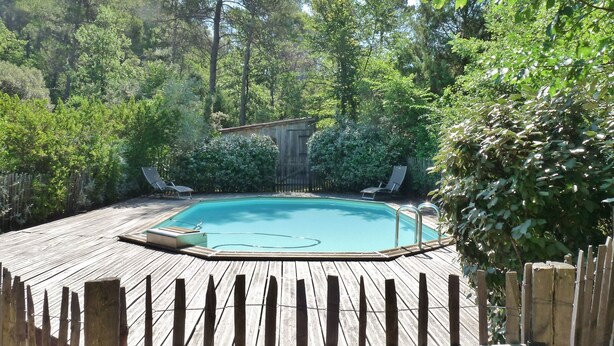 A wooden deck with a swimming pool, surrounded by lush greenery and trees. - In the heart of nature, a welcoming nest with swimming pool to recharge your batteries (Barjols)