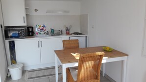 A compact kitchenette with a microwave, coffee maker, and a small sink. There is a dining table with two wicker chairs and a basket with a fruit. - In the heart of nature, a welcoming nest with swimming pool to recharge your batteries (Barjols)