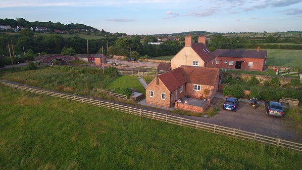 A rural property with a large barn, a small brick house, and a fenced field.