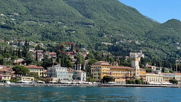 A coastal town with buildings along the waterfront, a prominent tower, and a mountainous backdrop.