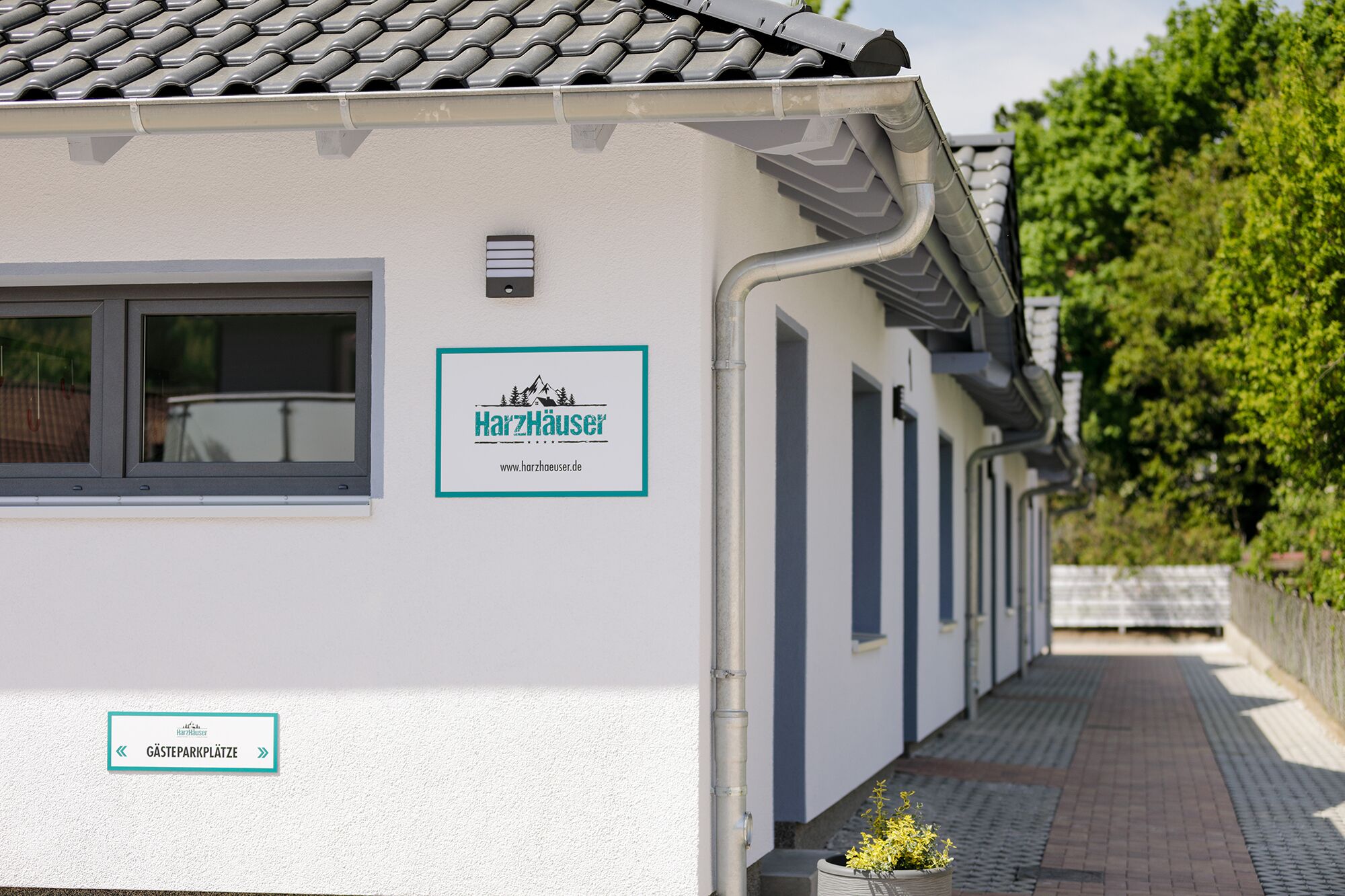 Ein Gebäude mit einem Ziegeldach, einem Schild mit der Aufschrift 'Gästeparkplätze' und einer Internetadresse für HartzHaus.de.