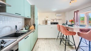 A modern kitchen with a central island, bar stools, and a view of the outdoors. - Luxurious home in Vodnjan (Vodnjan)
