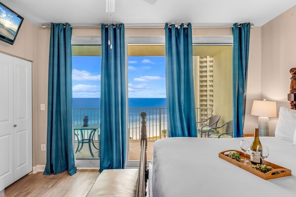 A hotel room with a bed, a tray with a bottle and glasses, and a balcony with a table and chairs.
