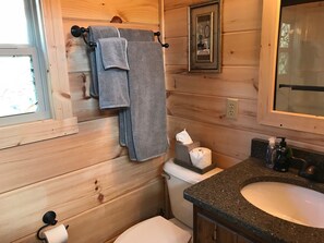 Een houten badkamer met een toilet, wastafel en handdoeken aan een rek.