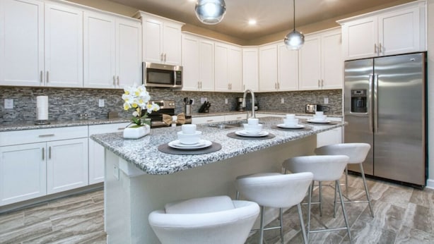 A modern kitchen with white cabinets, granite countertops, stainless steel appliances, and bar stools. - 4712 Fabulous & Brand-New Private Pool (Kissimmee)