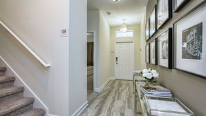 A hallway with a staircase, a door at the end, and a glass display case with items on the right. - 4712 Fabulous & Brand-New Private Pool (Kissimmee)