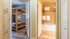 A bedroom with a bunk bed, wooden wardrobe, and a bathroom with a bathtub and shower. - Mammoth Green #105 - Nearly Ski-in Ski-Out Updated 2 Bedroom 2 Bath, Sleeps 6 (Mammoth Lakes)