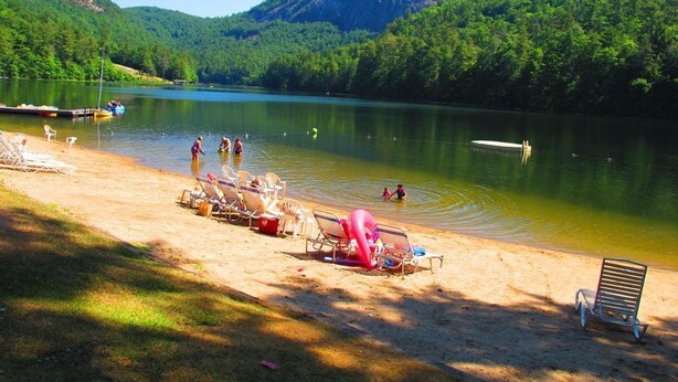 Una platja a la vora d'un llac, amb gandules i un moll.