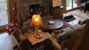 Interior d'una cabana acollidora amb una llar de pedra, parets de fusta, una gran decoració d'antlers de cérvol i una zona de seients confortable.