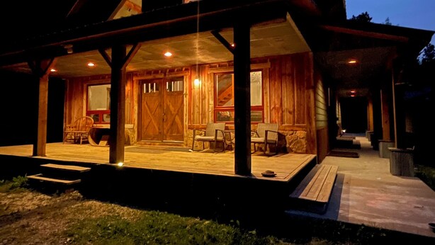 Une cabane en bois dotée d’un porche abrité, d’un coin repas et d’une grande fenêtre.