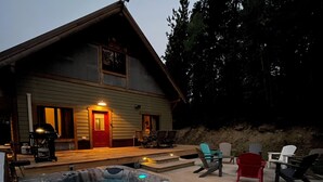 Un espace avec un bain à remous, une terrasse en bois, des chaises longues et, au fond, un bâtiment avec une porte rouge.