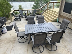 Un patio exterior con mesa y sillas, con vista a un lago.