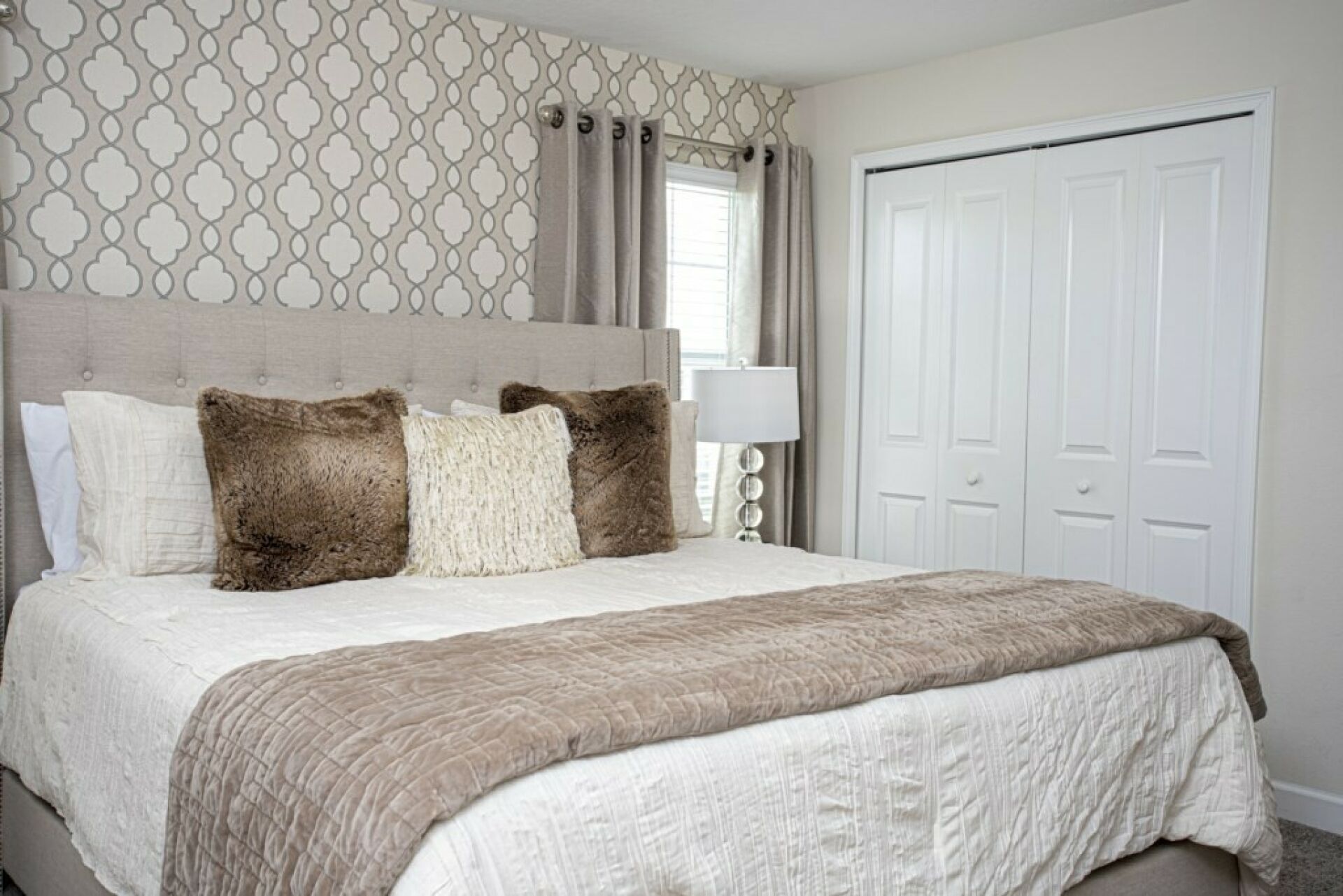 A bedroom with a large bed, a headboard, and a wardrobe.