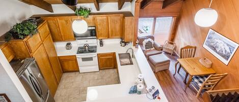 A modern kitchen with wooden cabinets, a central island, and a dining area with wooden furniture.