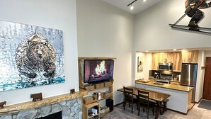 A living room with a fireplace, a television, and a dining area. - XL Luxury Penthouse. Top 1%. The Aspens. A/C, Pool, 3 hot tubs, ski-in ski-out.  (Whistler)