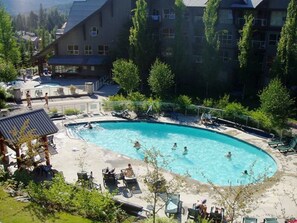 A pool area with lounge chairs and a building in the background. - XL Luxury Penthouse. Top 1%. The Aspens. A/C, Pool, 3 hot tubs, ski-in ski-out.  (Whistler)