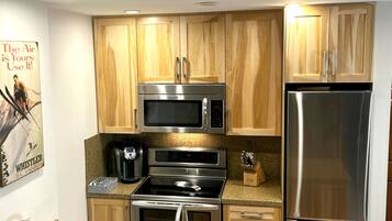Una cocina moderna con gabinetes de madera, electrodomésticos de acero inoxidable y encimera de granito.