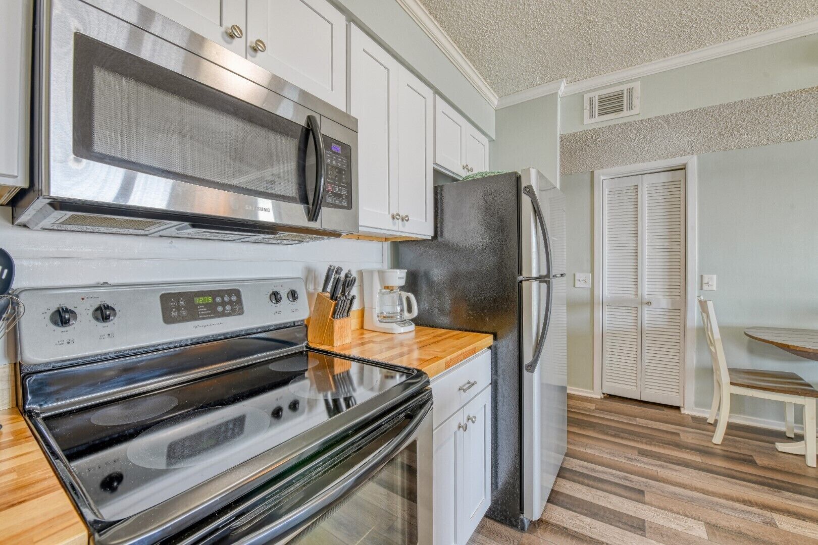 A compact kitchen with a microwave, stove, refrigerator, and a coffee maker on the counter.