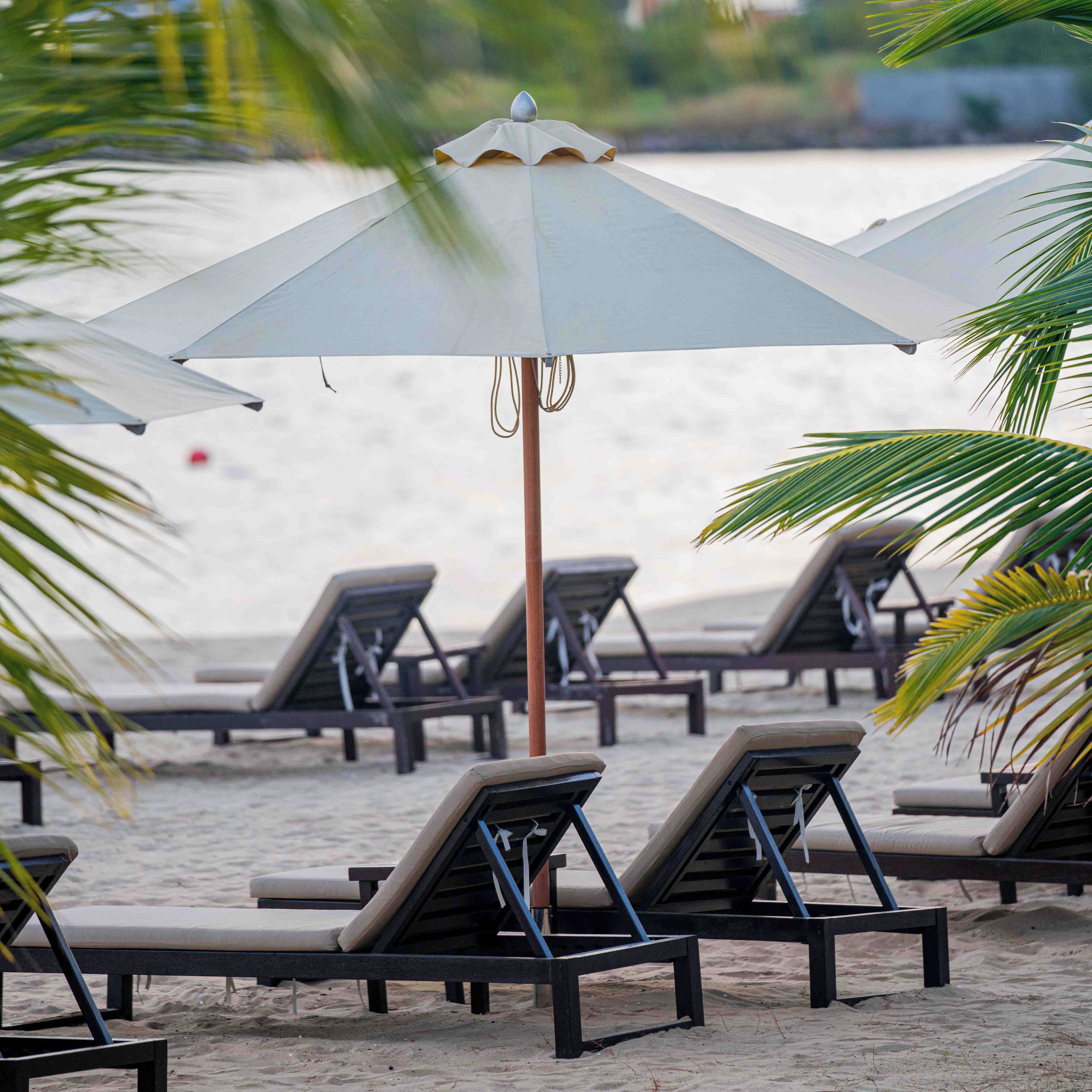 Am Strand, weißer Sandstrand, Liegestühle, Sonnenschirme
