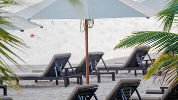 Am Strand, weißer Sandstrand, Liegestühle, Sonnenschirme
