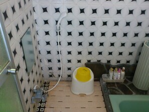 Ein Badezimmer mit Wandfliesen mit Muster, einer Dusche, einer Toilette und einem Waschplatz mit Toilettenartikeln.