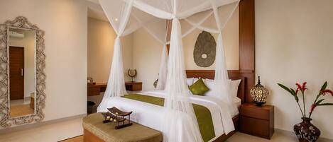 A hotel room with a four-poster bed, a bedside table with a lamp, a decorative mirror, and a small stool with a tray.
