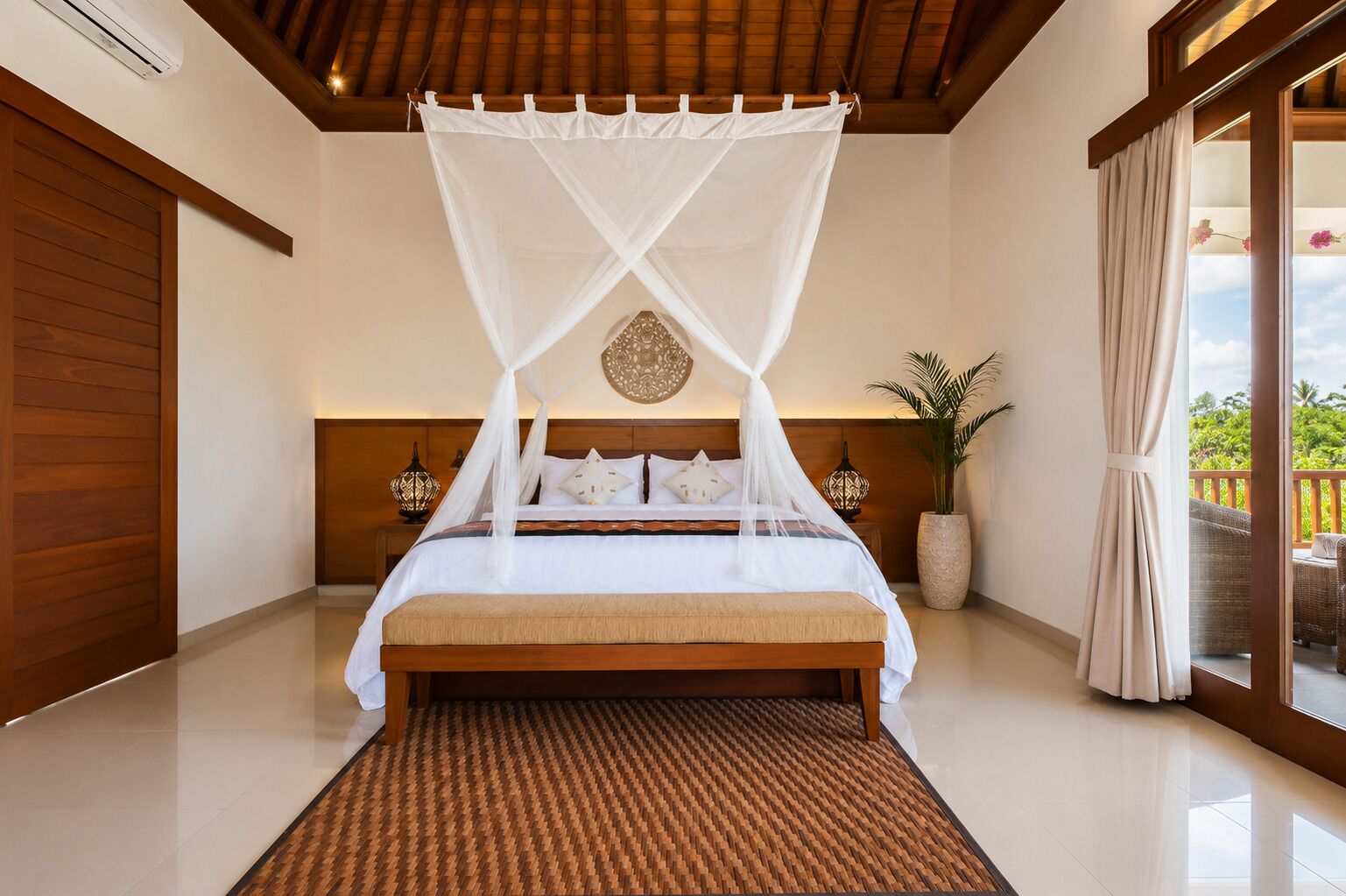 Ein Schlafzimmer mit einem Bett, einem Baldachin, einer Topfpflanze und Blick ins Freie.